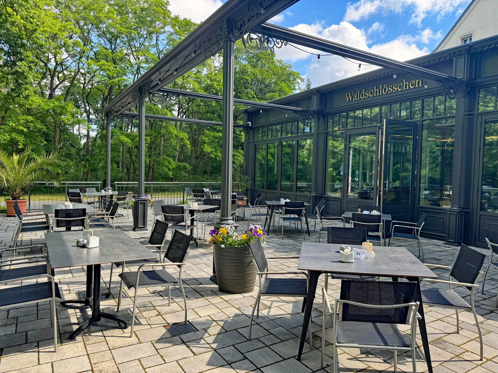 Terrasse mit Tischen unter dem Glasdach